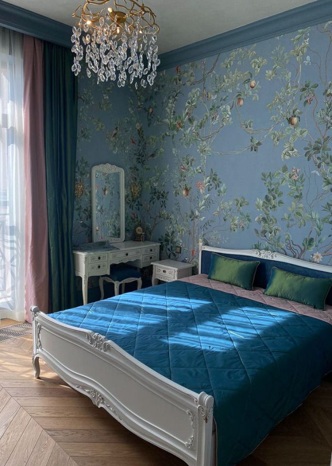 Кровать с синим покрывалом, синие обои с яблоками и цветами, розовые и синие шторы