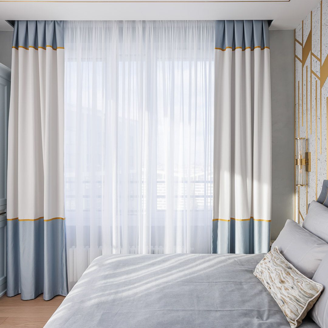 Белые с голубым шторы с золотым кантом в спальне 